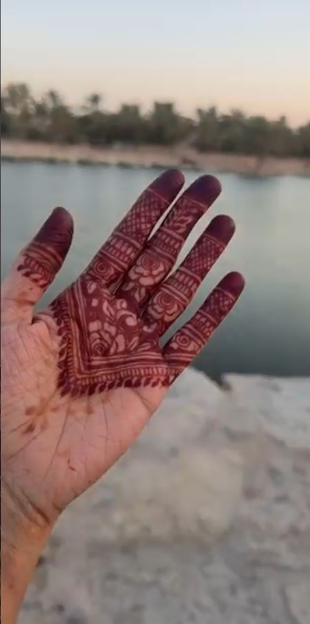 Bridal henna design on hand by the water at sunset